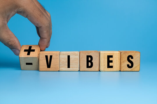 male hand flip wooden blocks with positive and negative vibes isolated on blue background