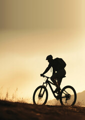 Fototapeta premium photo side view sillhuette of man riding a bicycle bike uphill with natural light.