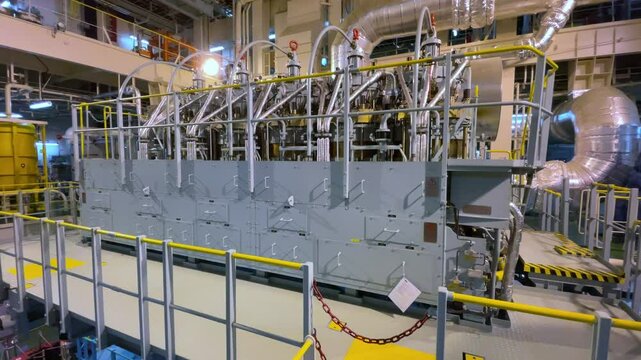 A large marine diesel engine stands in the ships engine room, surrounded by pipes, gauges, and controls, ready to power the vessel.