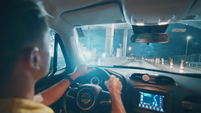 Pay for road with transponder. Adult man steers the car on a toll road during night and quickly passes the payment gate by using a transponder