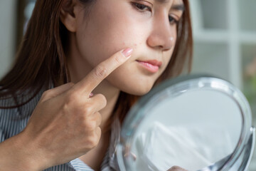 Self-Reflection and Skin Assessment. Pointing to a blemish while looking in the mirror.