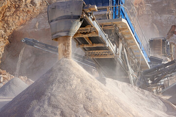 Stone crushing machine at open pit mining and processing plant for crushed stone. Conveyor belts and piles of gravel stone. Concepts of industry and building materials, sand and gravel