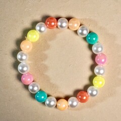 Cute round shiny rainbow bracelet beads accesories isolated on brown paper surface background.