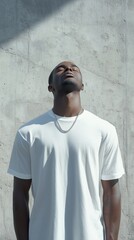 Obraz premium A man standing against a textured wall, wearing a white shirt, embraces sunlight with a serene expression and closed eyes.