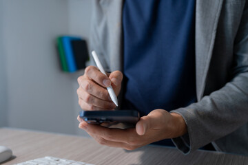 Close-up of a businessman's hands using a smartphone and a stylus