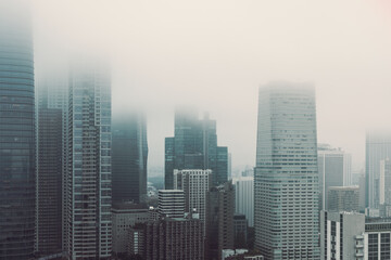 Obraz premium Hazy skyline of Tokyo with towering buildings enveloped in mist while the film effect enhances the muted tones and softens the urban architecture into a dreamlike scene