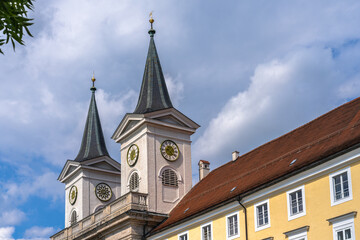 Close view of the double clock towers of St. Quirinus parish church in center of Tegernsee town on a sunny summer day with blue sky cloud, Bavaria, Germany