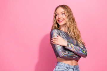 Blonde woman in shiny silver top posing happily with pink background