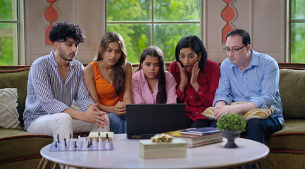 Indian family group mom dad son teen girl child watch film horror scene movie feel fear spend day time house Young adult man women sitting cozy sofa couch use laptop look screen have fun joy enjoy