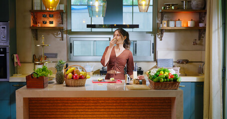  Indian happy young adult gen z woman lady standing indoor modern kitchen smiling hungry teen age girl female hold fresh apple slice fruit eat diet food spend time enjoy day