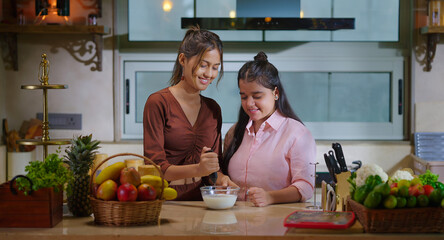 Indian happy young gen z woman lady hold spoon put ground powder mix in milk bowl. Adult female use mixing tool to make fresh coffee learn teen girl child talk gossip enjoy day spend time indoor home