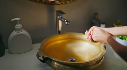 Close up of female use soap do hand wash in sink tap water for hygiene germ virus and safety indoor home daily routine good health care woman take liquid foam on wet palms clean finger dirty bacteria