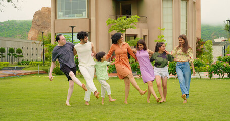 Indian happy family group dancing with teen girl child cute son kid boy enjoy day outdoor home park. Adult mom dad man woman young male female have fun joy play game spend time at outside garden house