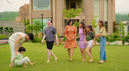 Indian happy family group play game running with cute son kid boy enjoy day outdoor home park Adult mom dad man woman young male female teen girl child have fun joy spend time at outside garden house