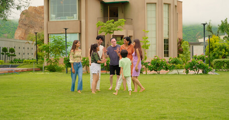 Obraz premium Indian happy family group play game running with cute son kid boy enjoy day outdoor home park Adult mom dad man woman young male female teen girl child have fun joy spend time at outside garden house