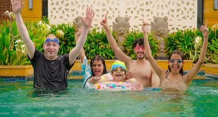 Indian happy family group with teen child look cam do funny pose enjoy outdoor resort pool trip Asian dad man male young adult girl boy female have fun joy spend day time at outside water park villa