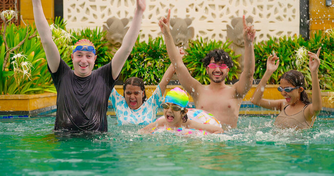 Indian happy family group with teen child look cam do funny pose enjoy outdoor resort pool trip Asian dad man male young adult girl boy female have fun joy spend day time at outside water park villa - Powered by Adobe