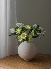 Bouquet of fresh alstroemelia flowers on a round wooden table