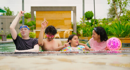 Indian happy family group with teen child dancing look cam enjoy outdoor resort pool edge trip mom...