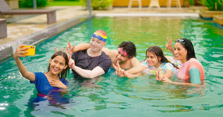 Indian happy wet cute teen girl boy young mom hold mobile look cam take selfie make pose water pool resort mom dad adult child use phone record shoot video spend time have fun joy outdoor hotel trip