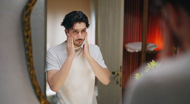 Indian Asian gen z young adult single happy man male guy smiling look mirror touch beard daily care routine feel proud good ready for new Joyful day enjoy indoor house