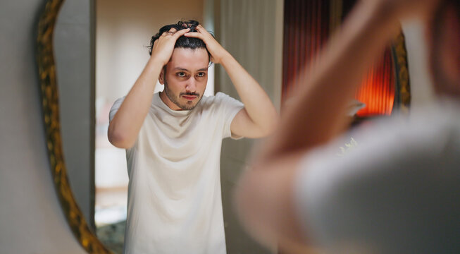 Indian Asian gen z young adult single happy man male guy look mirror touch daily care routine feel proud shows good comb hair with finger ready for new day Joyful enjoy indoor house