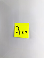 Colored sticky note with the word open. Open written on sticky note on white background. Opening concept, simple design with the word Open, vertical photo