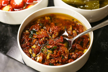 Sun-dried tomatoes in olive oil served as a snack. Appetizing bowl with flavorful dried tomatoes...