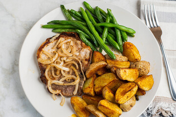 pork chop top with onions  with green beans and potato wedges