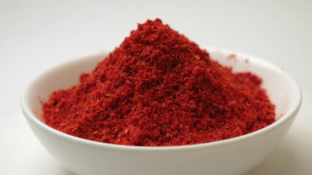 Paprika powder is a fragrant spice made from sweet varieties of capsicum. red paprika spice powder in a white cup on a light background