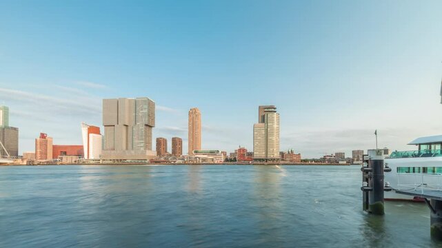 Panorama showing Rotterdam skyline timelapse from Nieuwe Maas River bank to Wilhelminapier and Kop van Zuid. Modern skyscrapers, ferry station and Erasmus Bridge, waterfront with boats passing by