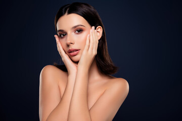 Captivating portrait of a young gentle woman with natural makeup against a dark blue backdrop