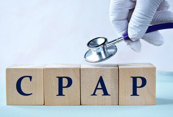 Cubes with the abbreviation CPAP in the hand of a doctor. Medical concept