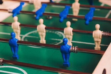 Fototapeta premium Group of friends playing kicker in a sports bar room, colleagues teammates play table football, table soccer game in the office, having fun, tabletop football match competition at work, backyard games