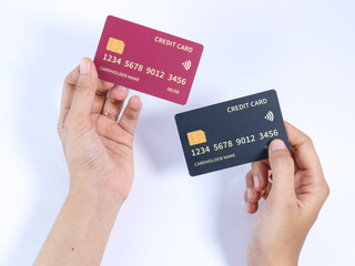 Two hands holding red and black credit cards on a white background, featuring chip and contactless payment symbols