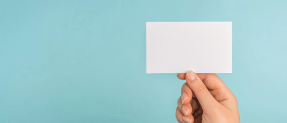 Obraz premium hand holding blank postcard against light blue background, symbolizing communication and creativity
