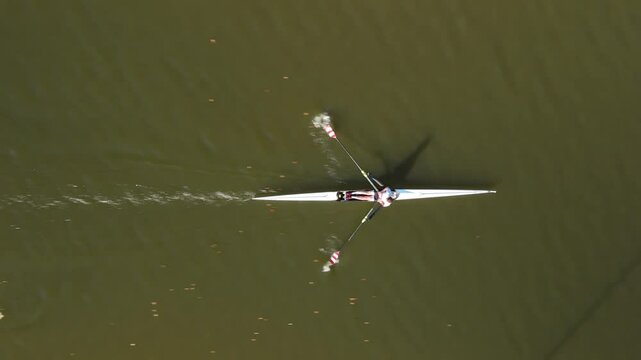 Rowing on a calm river in the early morning sun with a single sculler