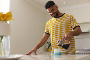 Smiling man in striped shirt pouring coffee in kitchen, enjoying morning routine, copy space