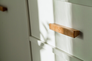 Beautiful sunset shadows and the sun on the white facade of the cabinet with wooden handles