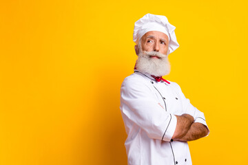 Portrait of a male chef wearing a traditional uniform on a yellow background emphasizing culinary expertise and a confident personality