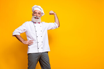 Energetic senior male chef posing confidently in a professional uniform against a bold yellow background
