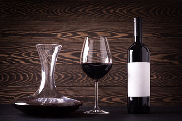 Decanter, glass and bottle with red wine on wooden rustic background