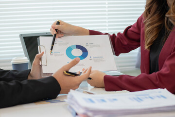 Businessman and woman discussing and using market analysis chart to reduce investment risk and using calculator.