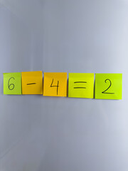 Simple math equation with subtraction of number. Six minus four equals two. Vertical photo of color...