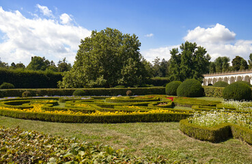 Obraz premium Exterior environment of a botanical garden with cultivated ornamental shrubs and plants. Sunny day in a botanical garden. Summer, travel. In the background a colonnade with ornamental columns, sky