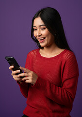 Naklejka premium A studio portrait of a young beautiful Indonesian Asian woman in a casual red sweater, looks laugh while typing on her phone. isolated on purple background