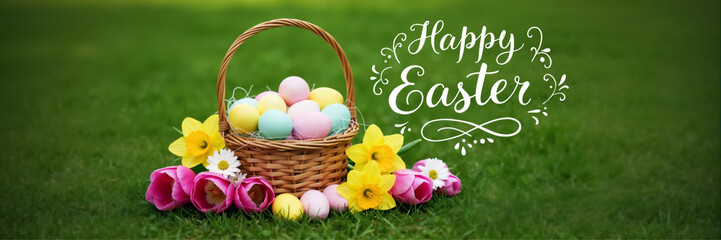 Naklejka premium Happy Easter lettering on greeting horizontal banner with basket of pastel colored eggs and spring daffodil, tulip flowers on green grass lawn