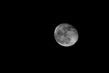 A natural view of the moon partially covered by soft clouds in the night sky. A serene and atmospheric scene capturing the beauty of the celestial landscape