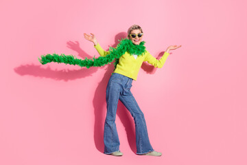 Cheerful young woman in trendy outfit gesturing with joy against a vibrant pink background showcasing stylish fashion creation