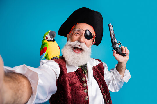 Photo portrait of old funny pirate male take selfie photo hold pistol dressed carnival party costume party isolated blue color background